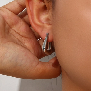 Close-up of geometric silver stainless steel hoop earrings with polished diamond-cut finish