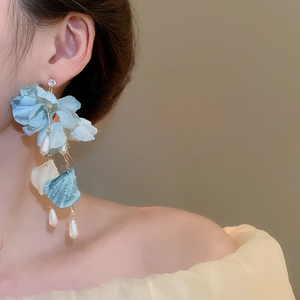 Detail of blue and white fabric flower earrings with pearls and gold tassel on model