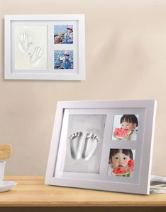 Detail von DIY Baby Handabdruck und Fußabdruck Bilderrahmen auf Holztisch und beiger Wand