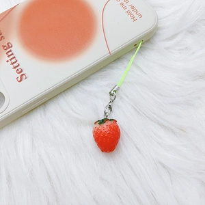 Macro shot of a cute red resin strawberry charm with green cord and silver lobster clasp