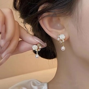 Close-up of French baroque earrings with white camellia flowers and round pearl pendants