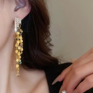 Macro view of long gold tassel earrings with glittering sequins and white rhinestones