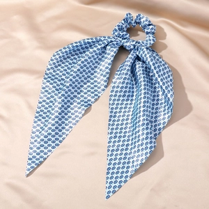 Detail of silk hair scrunchie with blue evil eye sun print and long ribbon streamers