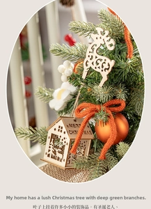 Close-up of a mini Christmas tree with wooden house, reindeer ornaments and orange bows