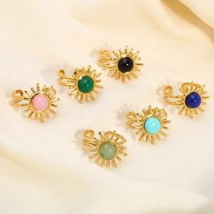 Detailed view of sunburst gold rings set with colorful gemstones on silk fabric