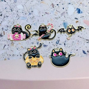 Five Halloween black cat enamel charms featuring pumpkins, bats, and candy designs