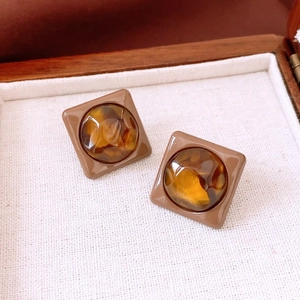 Détail de boucles d'oreilles carrées vintage avec incrustations en résine ambre