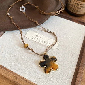 Detailed macro view of a brown resin flower pendant on a woven cord necklace