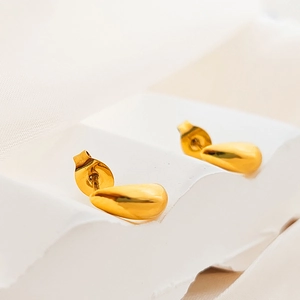 Dettaglio di orecchini a goccia placcati oro 18K su espositore in pietra bianca