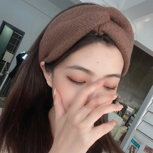 Detail of a brown knitted cross headband showing soft textured fabric and twisted knot