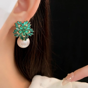 Detail of emerald gemstone flower earring with a large white pearl drop on model
