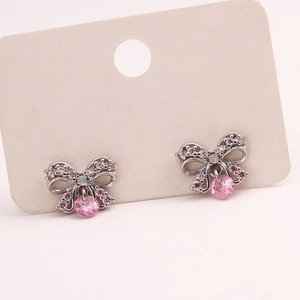 Detail view of silver bow stud earrings with pink crystals on a display card