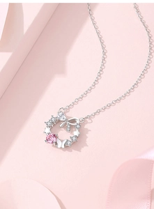 Macro detail of silver floral pendant with pink gemstone and butterfly bow design