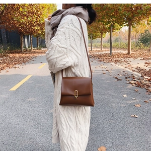 Sac bandoulière en cuir caramel avec fermoir doré porté par un mannequin en style urbain