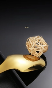 Macro shot of mirror-polished golden stainless steel tea spoon on black background