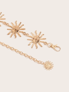 Détail d'une chaîne de taille en métal doré avec pendentifs soleil pour femmes
