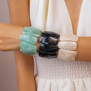 Detail of three acrylic rectangle bangles with marble texture in mint, black and cream