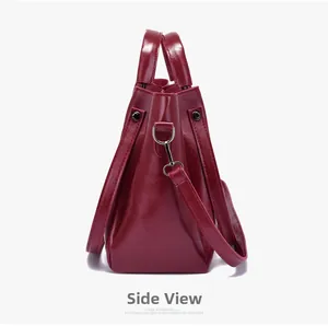 Macro side view of burgundy glossy leather handbag showing metal rings and stitching details