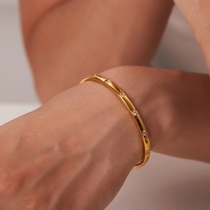 Bracelet en acier inoxydable doré avec zircons blancs sur poignet féminin
