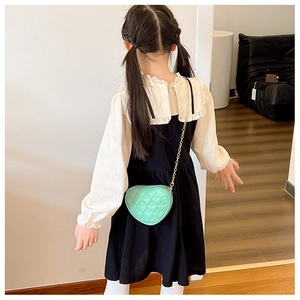Girl wearing a mint green heart-shaped quilted crossbody bag with gold chain strap