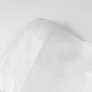 Detailed close-up of white strapless dress showing woven fabric texture and stitching