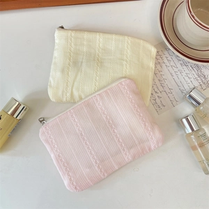 Detailed view of quilted lace knit makeup bags in cream yellow and soft pink pastel colors