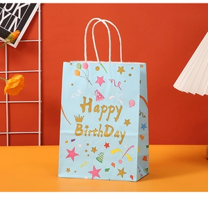 Close-up of blue paper birthday gift bag with golden Happy Birthday text and balloons