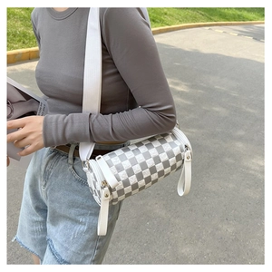 Close-up of a grey checkered cylinder crossbody bag with a wide strap on model