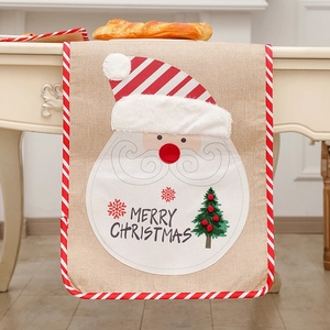 Linen Christmas table runner with Santa Claus embroidery and festive white pom-poms