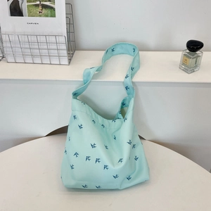 Detail of light blue canvas tote bag featuring bird print in a minimalist setting