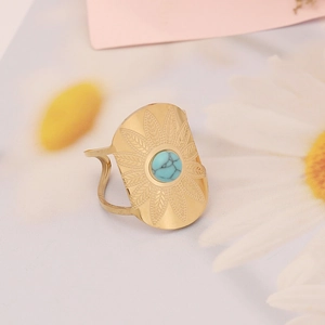 Macro shot of gold stainless steel ring with turquoise stone and feather engraving