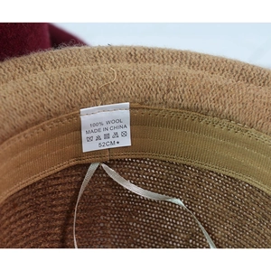 Detail view of the 100% wool label and inner breathable knit texture of the kids' brown hat
