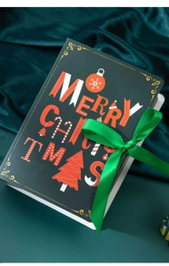 Detailed view of magic book style Christmas gift box with green ribbon on velvet background