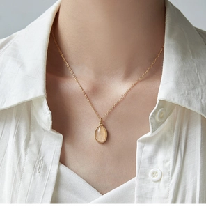 Close-up of a teardrop-shaped light yellow gemstone pendant necklace in 18K gold finish