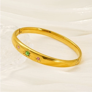 Gros plan d'un bracelet en acier titane doré orné de pierres colorées en étoile