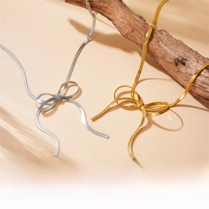 Detailed shot of bow pendant necklaces in gold and silver finish with snake bone chains
