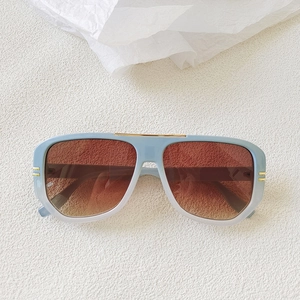 Close-up of light blue gradient oval sunglasses with gold metal top trim accents