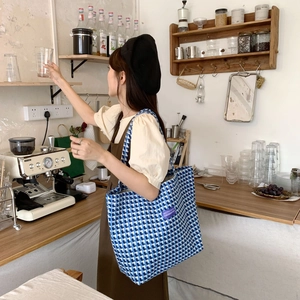 Close-up of blue plaid wool tote bag showing side view and large capacity on model
