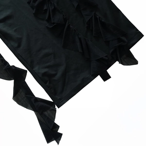 Detailed view of layered ruffle hem and sheer mesh fabric on a sexy black dress