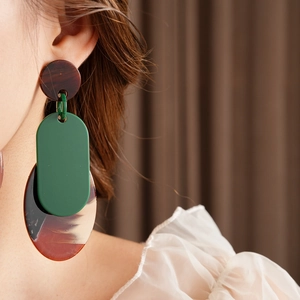 Detail of vintage geometric resin earrings in green and amber on model