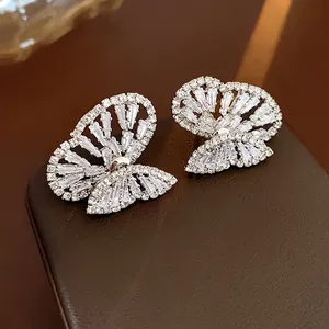 Macro shot of butterfly stud earrings with sparkling cubic zirconia on premium leather