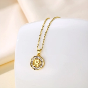 Macro shot of 18K gold letter R pendant with baguette-cut sparkling zircon stones