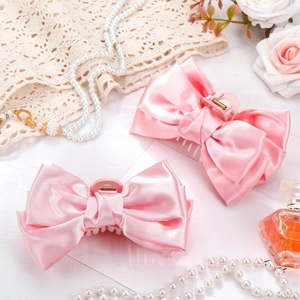 Elegant pink satin bow hair claw clips with pearls and roses in a luxury lifestyle setting