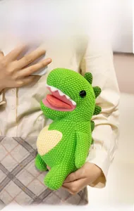 Detail of green knitted dinosaur plush toy with a soft heart pattern and spikes