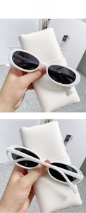 Close-up of retro white oval sunglasses with grey lenses and a white leather pouch