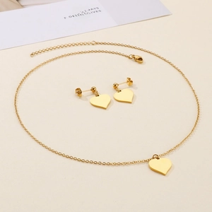 Flat lay of a gold heart jewelry set with polished necklace and matching stud earrings