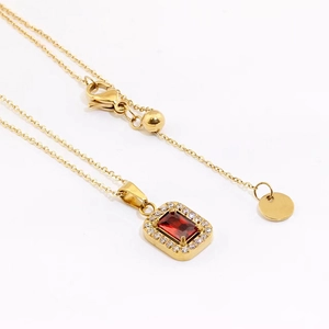 Detail view of gold necklace featuring red rectangular gemstone and zircon accents