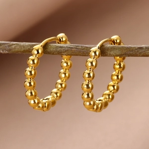 Detailed macro view of 18k gold plated beaded hoop earrings on a natural wood branch