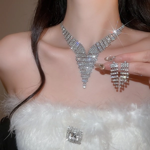 Close-up of sparkling V-shaped tassel diamond necklace and earrings jewelry set on a model