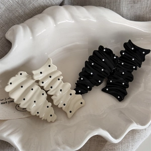 Detail of wavy dot pattern hair clips in black and cream on a decorative shell plate